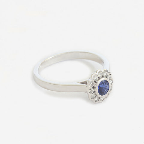 a white gold modern sapphire and diamond round cluster ring in rub over setting