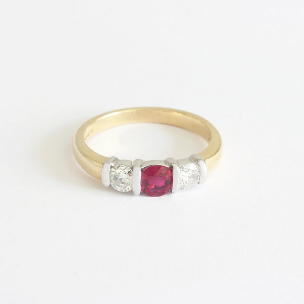 a gold 3 stone ring with one ruby and 2 diamonds 