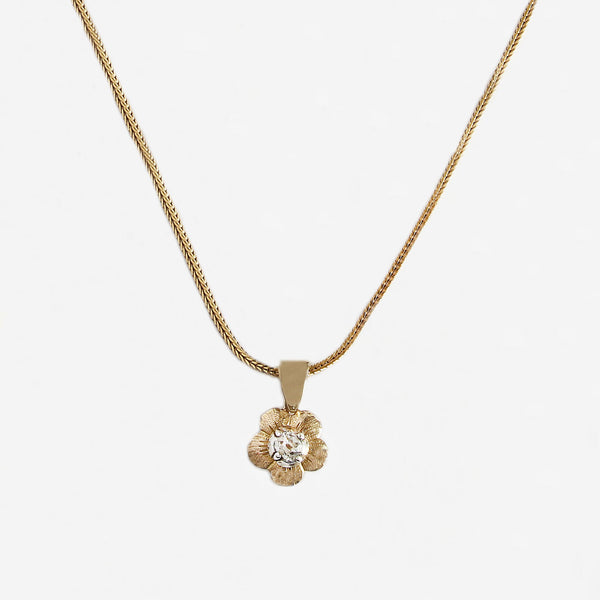 a flower pendant with a diamond on a yellow gold chain