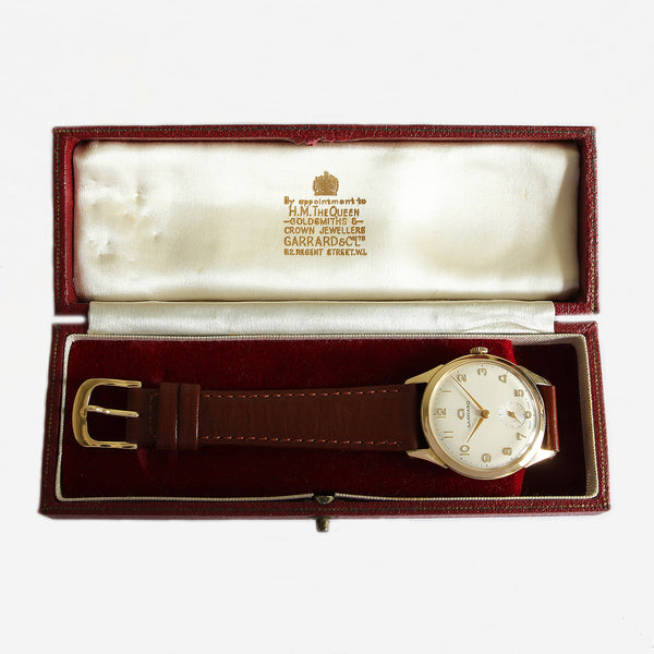 a vintage secondhand garrard watch with gold case and brown leather strap and box