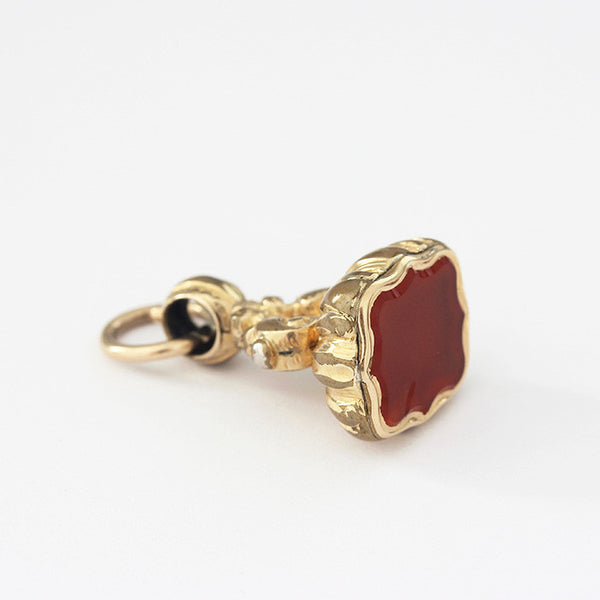 a plain gold plated seal fob charm with pattern on the edges